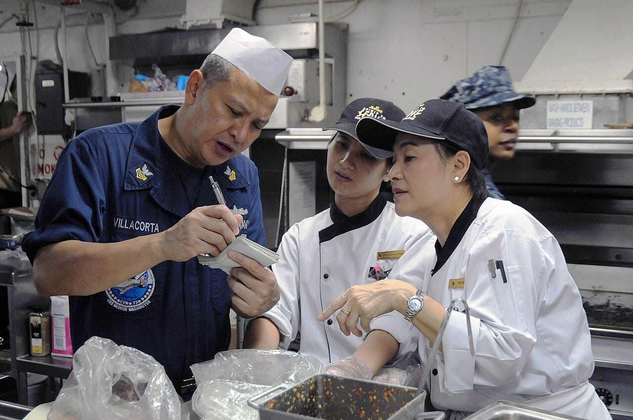 US Navy 110809-N-JV466-035 Culinary Specialist 1st Class Resty Villacorta, from Nueva Ecija, Philippines, reviews a recipe with Thai chefs