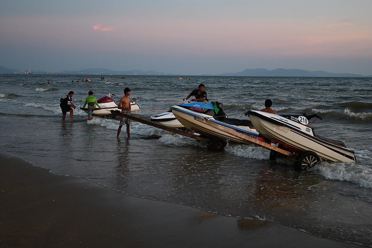 DFC 5140 Evening at Pattaya locals prepare jet skis on the shoreline as the sun sets over the Gulf of Thailand