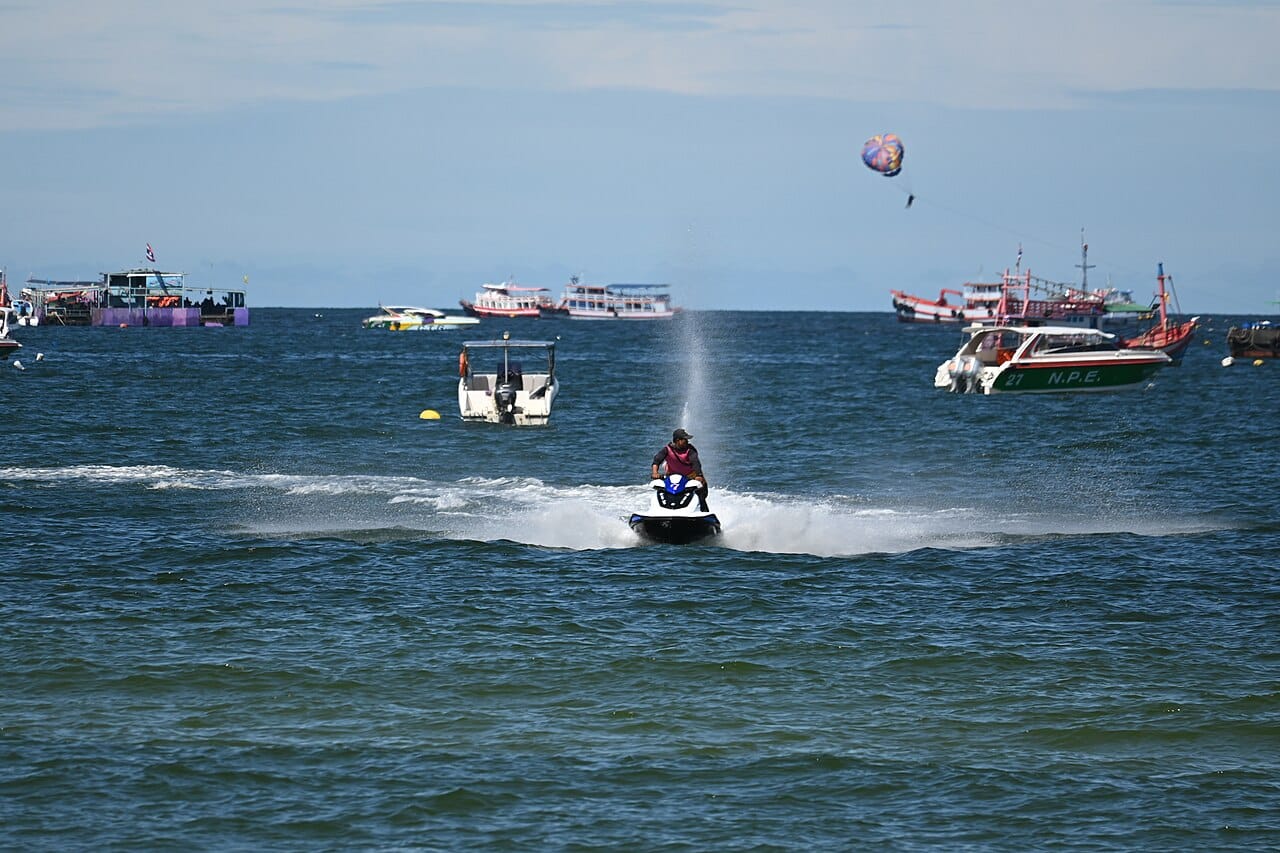 DFC 1455 A person zipping across the ocean on a jet ski with boats and a parasail dotting the horizon on a sunny day